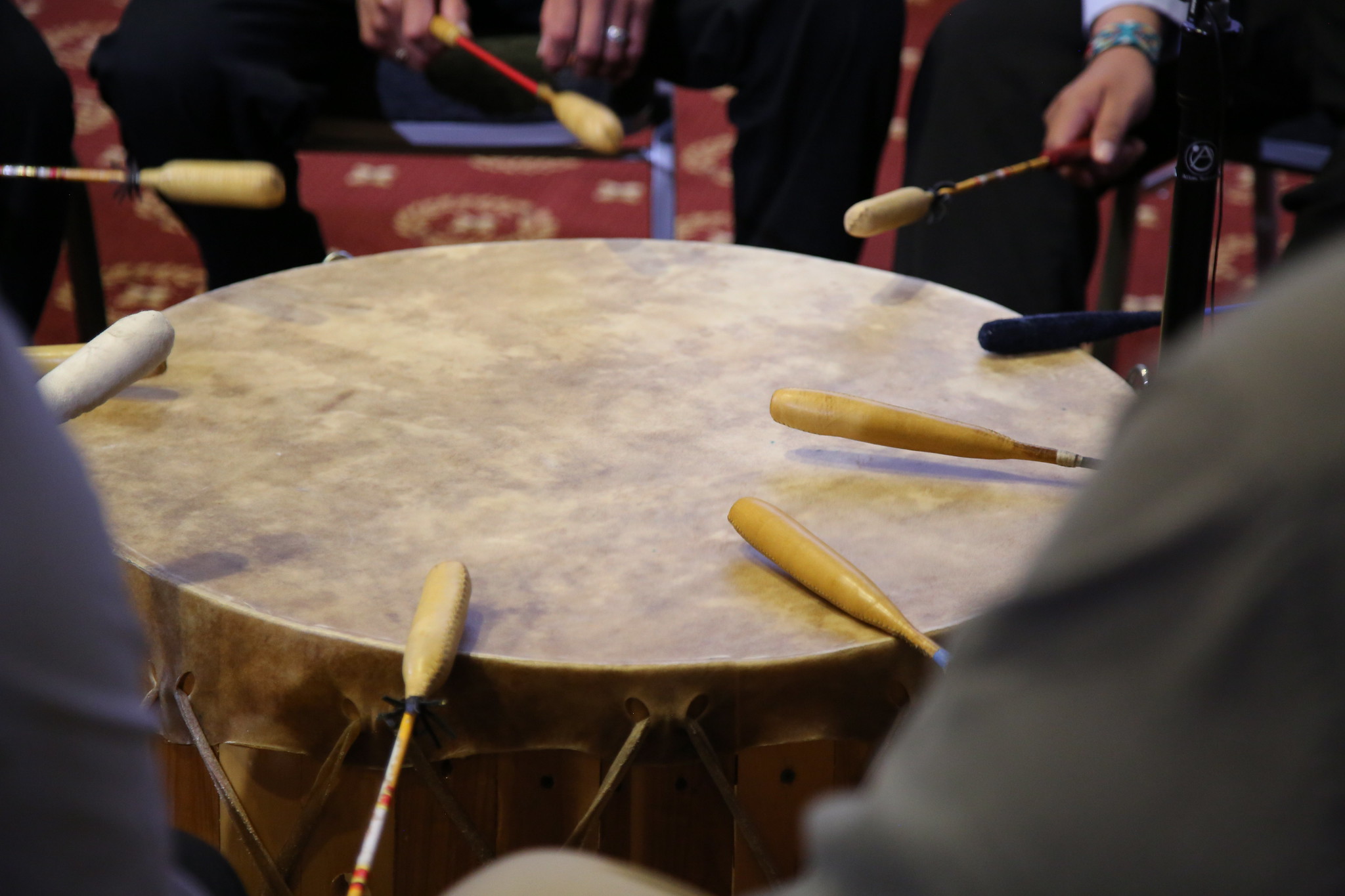 padded sticks striking a circular ceremonial drum