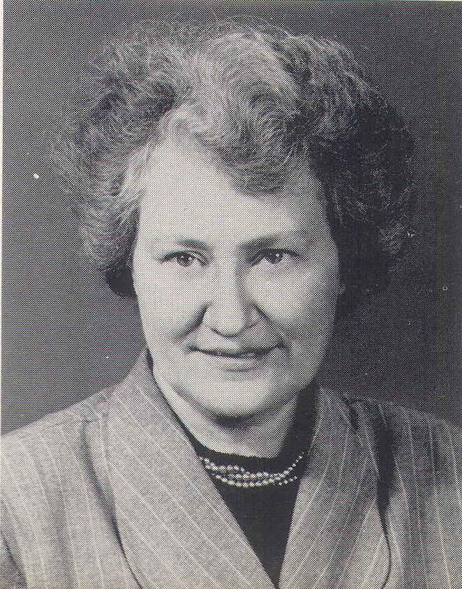 black and white photograph of Emma Smith Hough, showing an older white woman with a halo of graying hair, an assured smile, and wearing a plaid blazer and a triple strand of pearls..