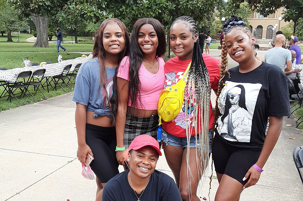 a group of smiling Black students posing for the camera at an event in front of Shryock Auditorium